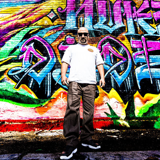 Artist in front of graffiti wall