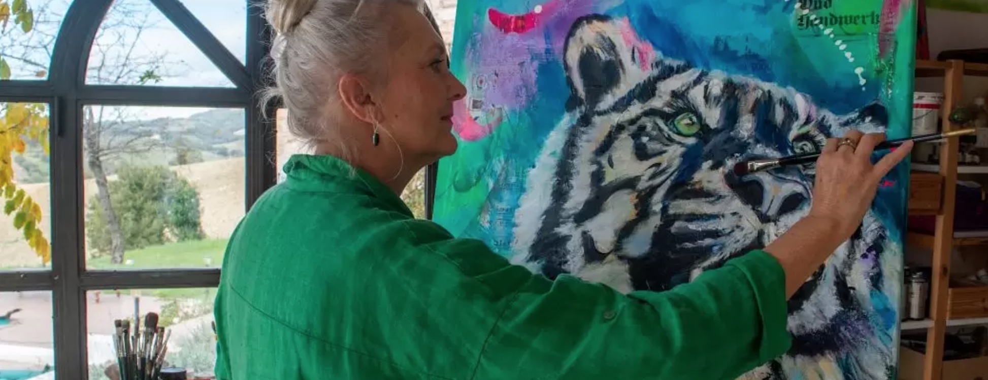 Woman painting colorful art canvas of black and white tigger on blue green paint