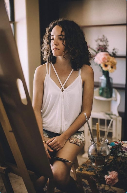 Artist Sitting At Easel with flowers in background