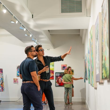 men in gallery looking at paintings on walls