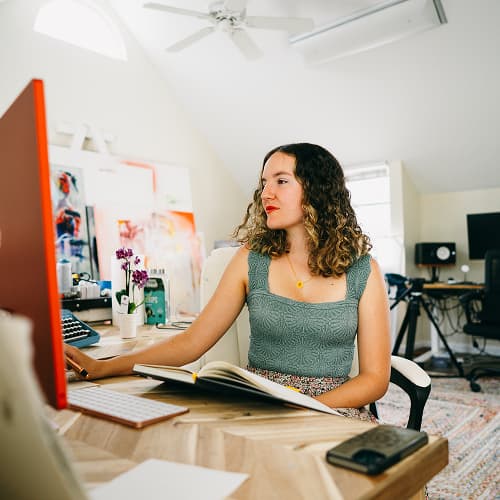 woman writing on journal at computer