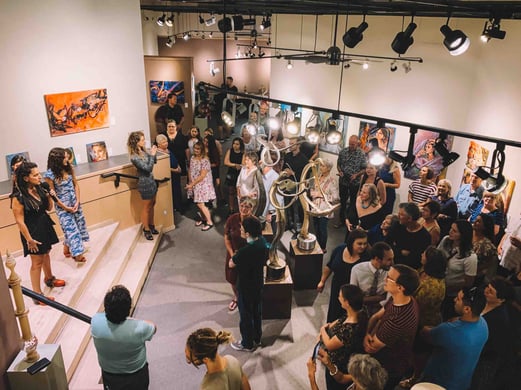 people in crowd in front of stage in art gallery