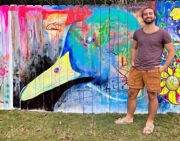 Jake Dunn in front of art mural of blue duck