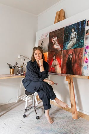 artist sitting in studio space with red orange green blue art 