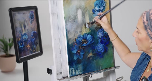 Woman in blue painting on canvas blue flowers on cream and green background