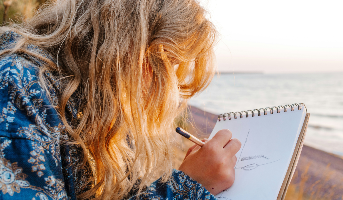 Woman sketching at ocean on drawing pad