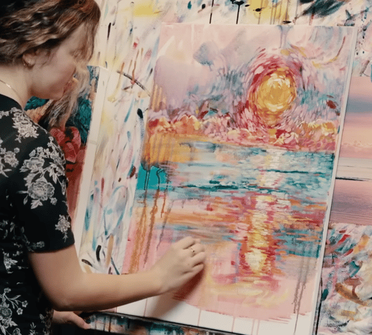 girl painting landscape with red green pink yellow