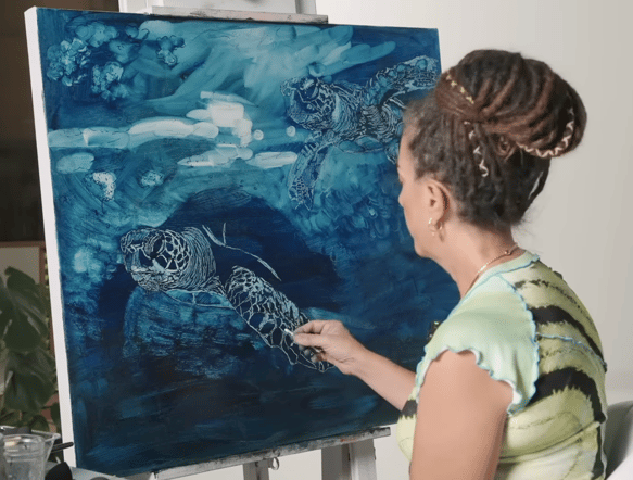 woman painting turtle on blue canvas