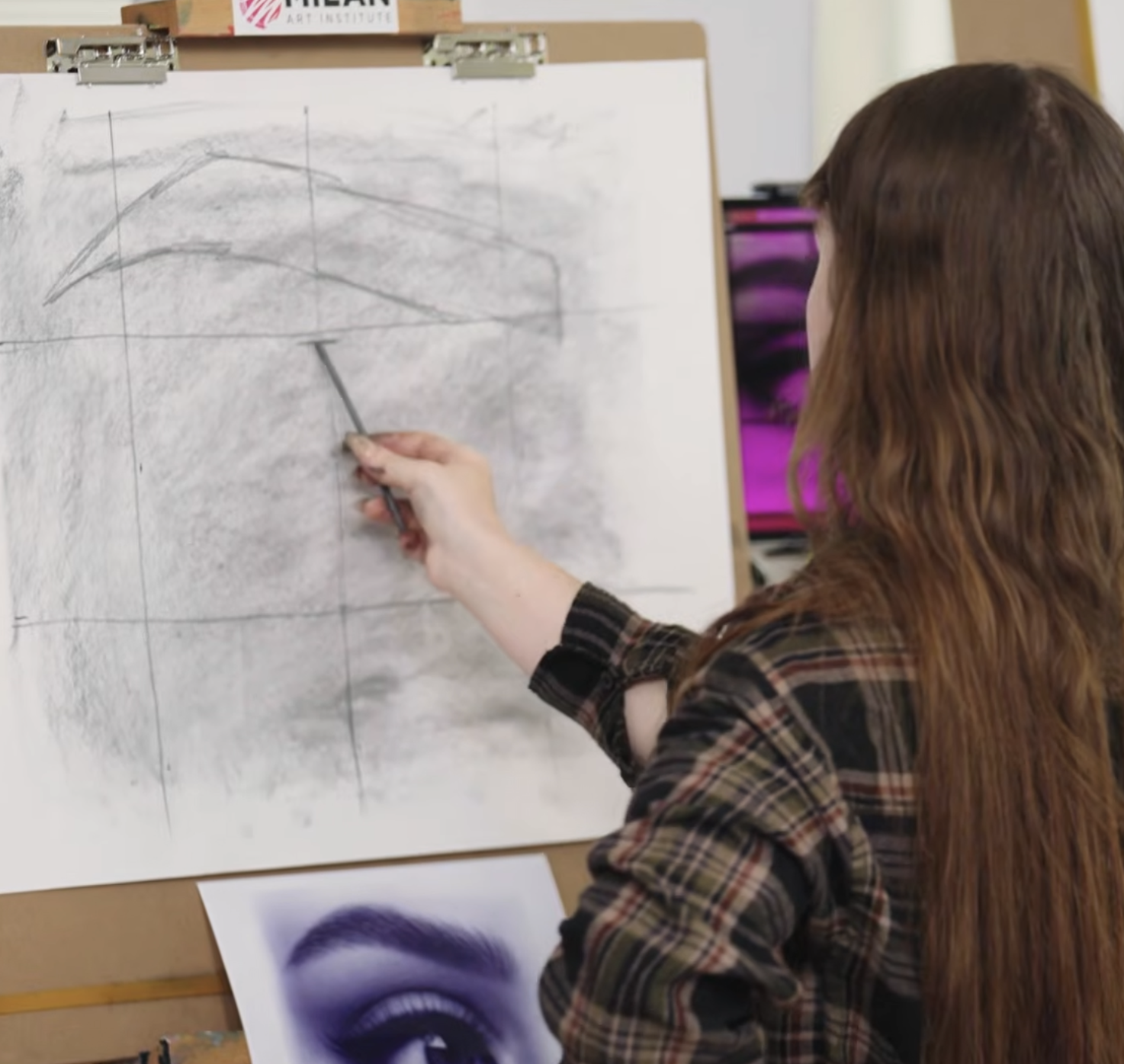 Artist drawing with pencil on paper on easel