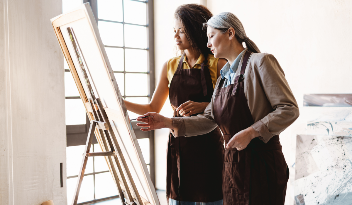 Teacher and artist conversing in front of easel